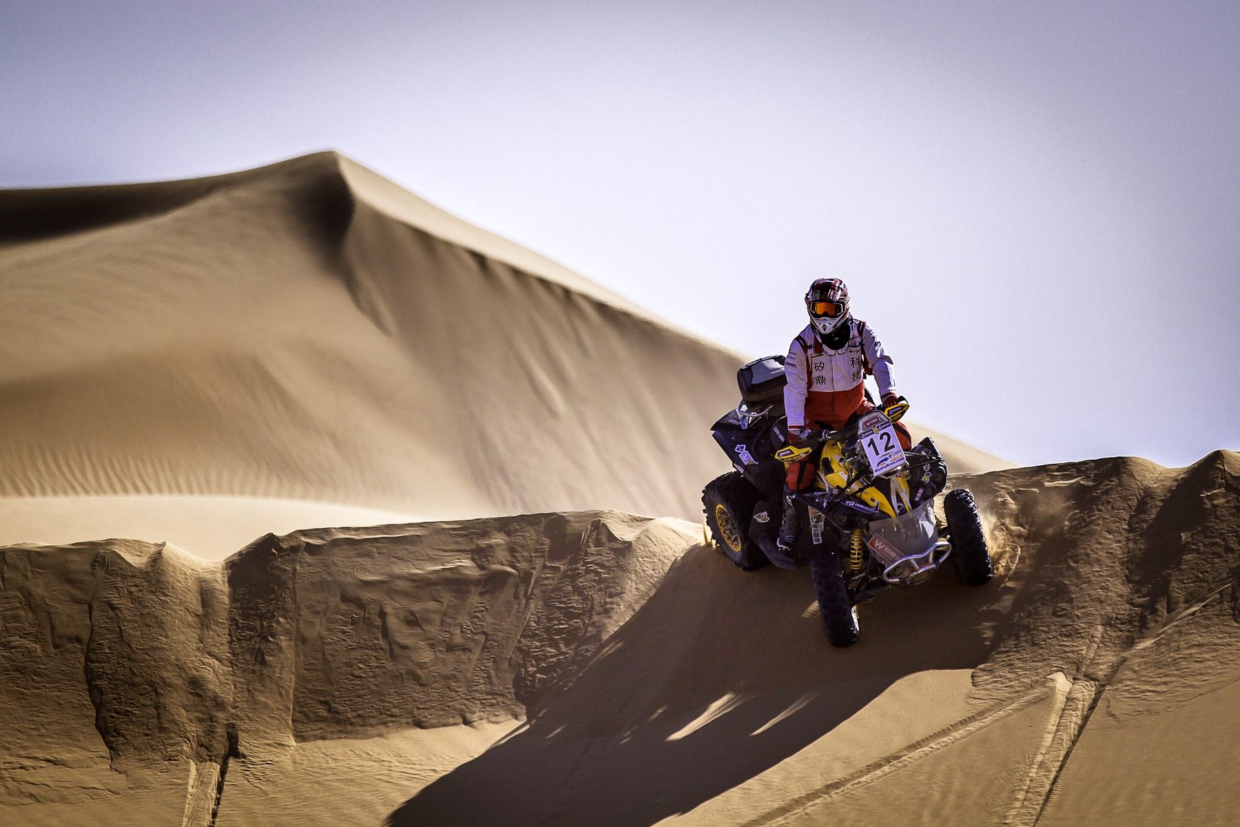 James TJ Lee riding an ATV down a steep desert ridge