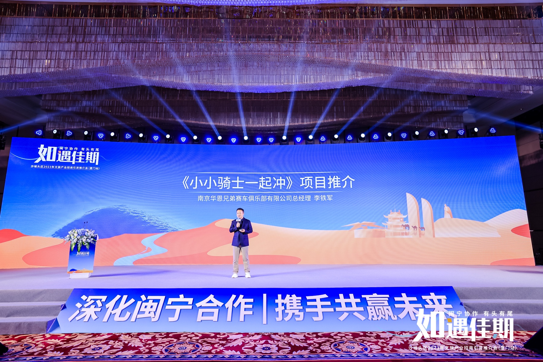 James TJ Lee presenting Little Knights, Let’s Go! on a large blue stage at a 2023 cultural-tourism roadshow in Xiamen.