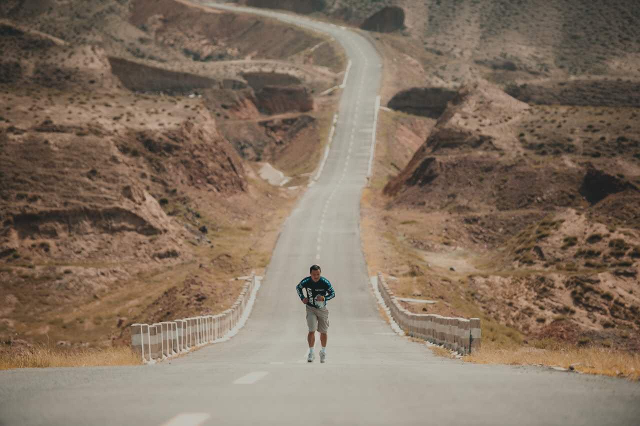 James TJ Lee training alone on a long road through an arid landscape