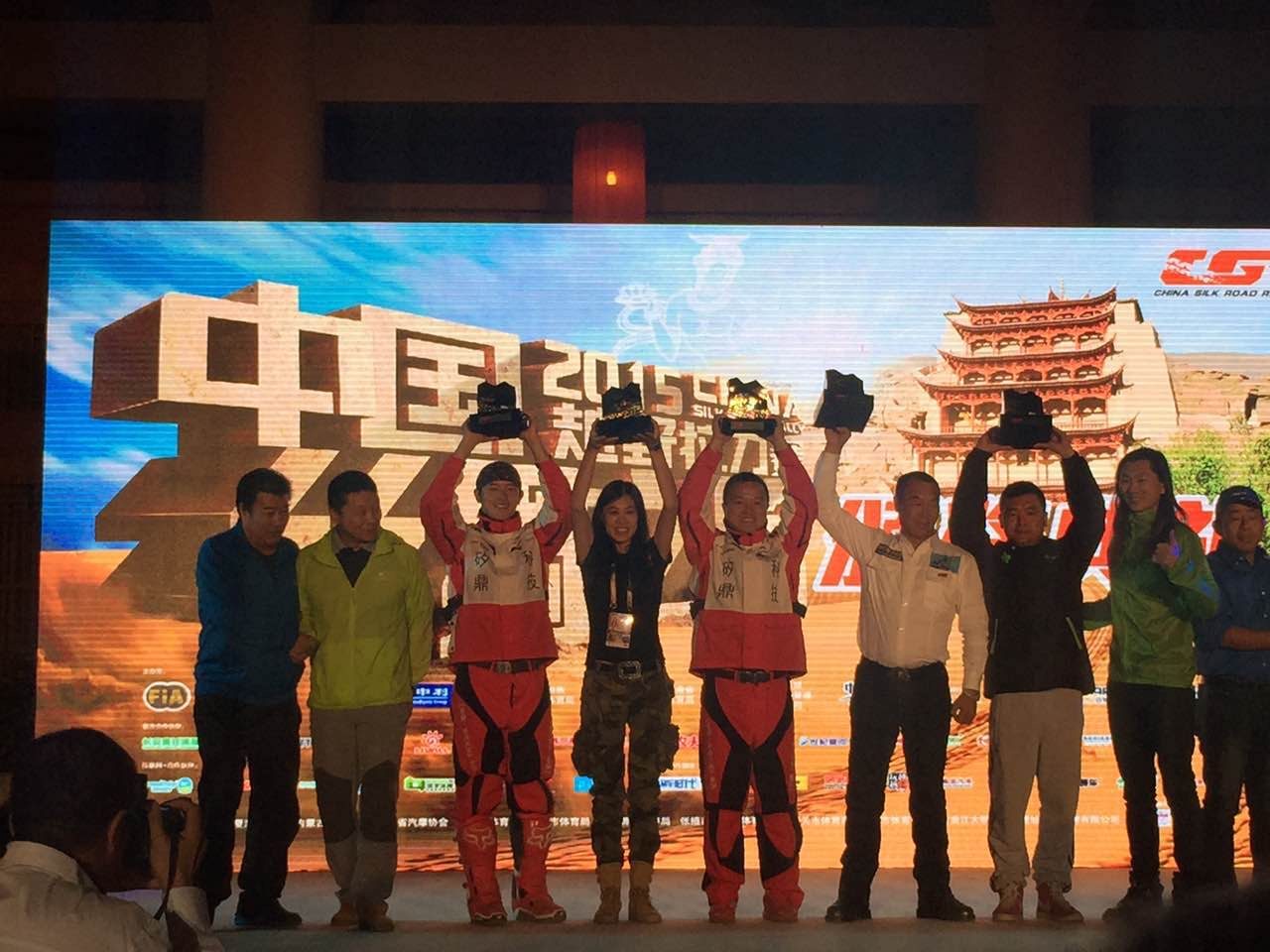 Members of James TJ Lee's rally team raising trophies onstage in 2015.