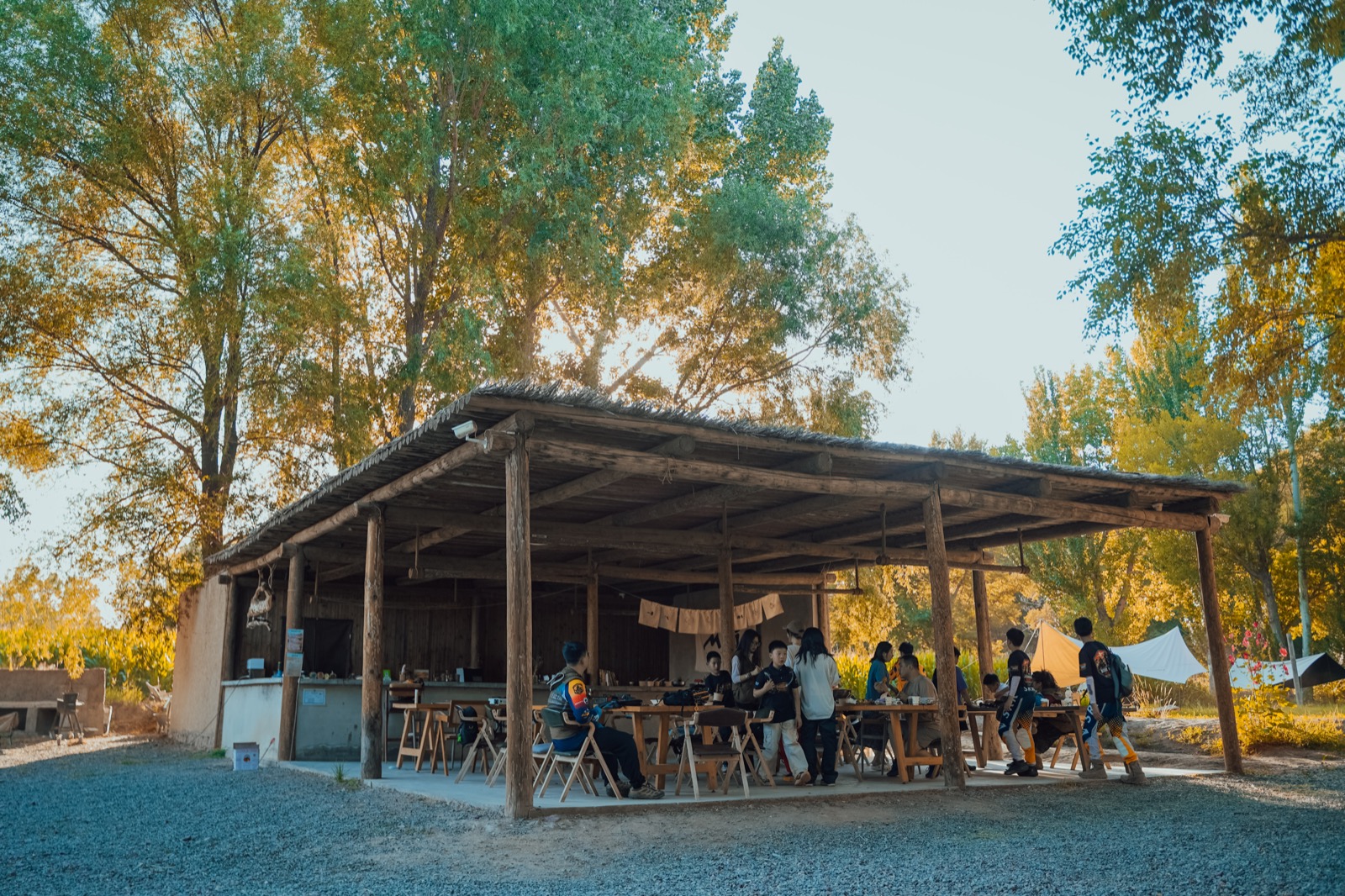 Children, families, and guides sharing an ordinary program day at a shaded outdoor base